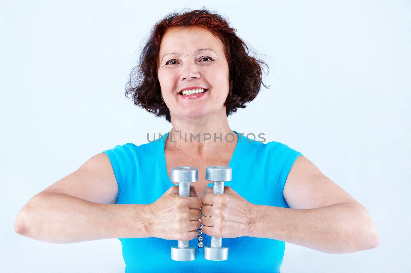 Portrait of middle-aged female doing physical exercise with dumbbells