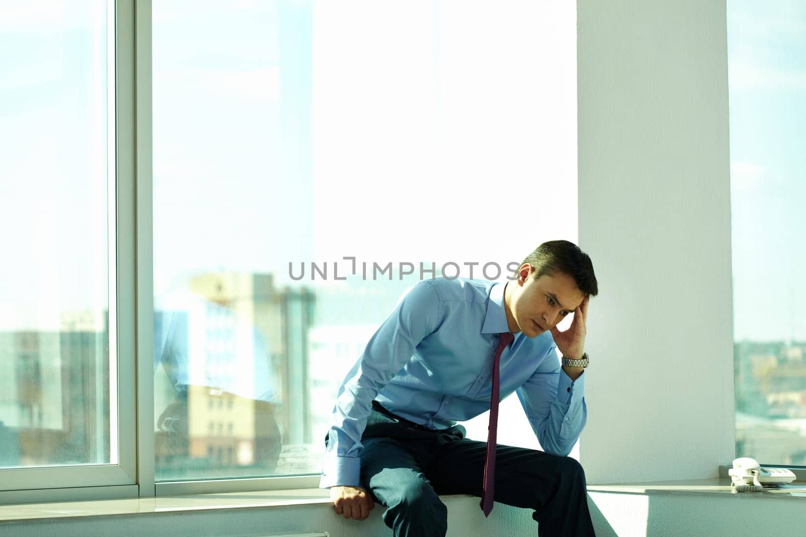 Portrait of thoughtful man sitting by window in office
