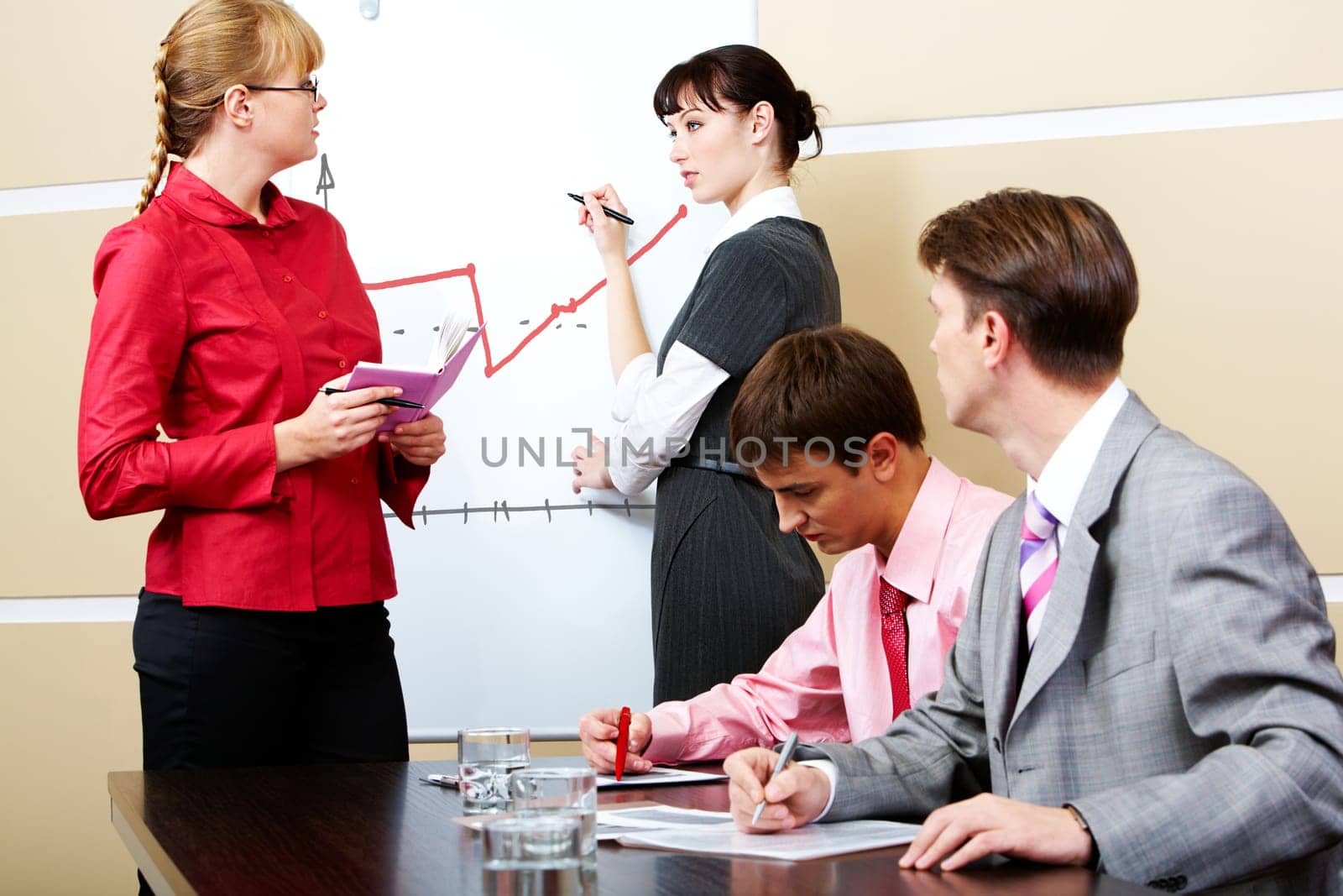 Student and teacher looking at each other at whiteboard with two men staring at them
