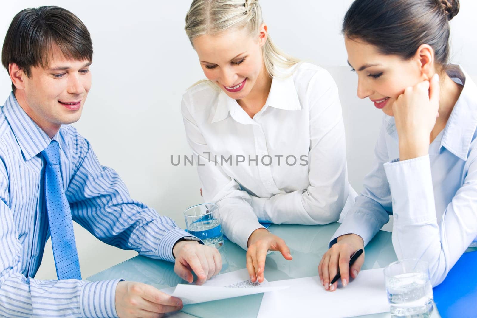 Photo of business partners looking at document and discussing it at meeting
