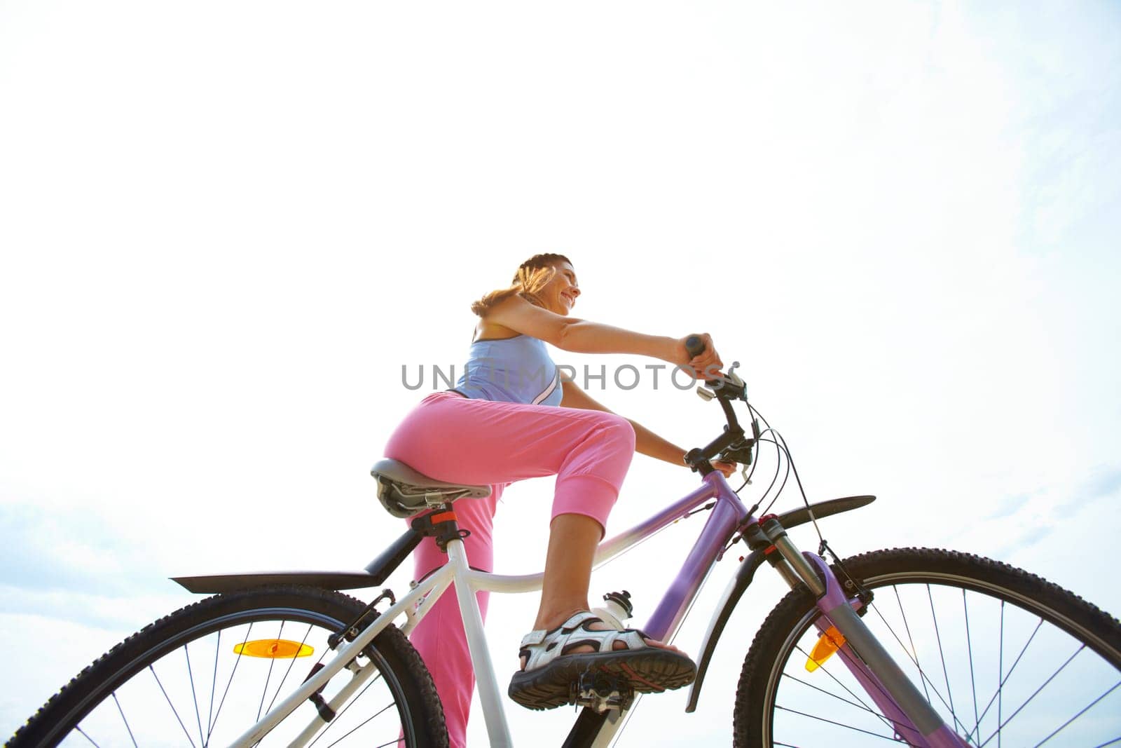 Below view of young woman riding bicycle
