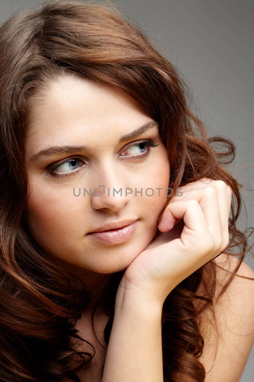 Portrait of charming girl touching her face and looking aside