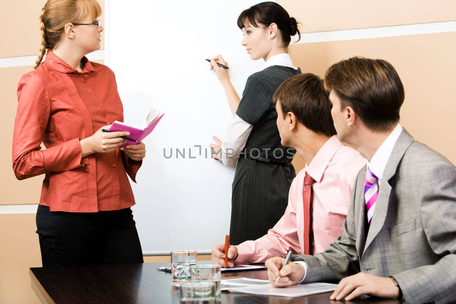 Student and teacher looking at each other at whiteboard with two men staring at them