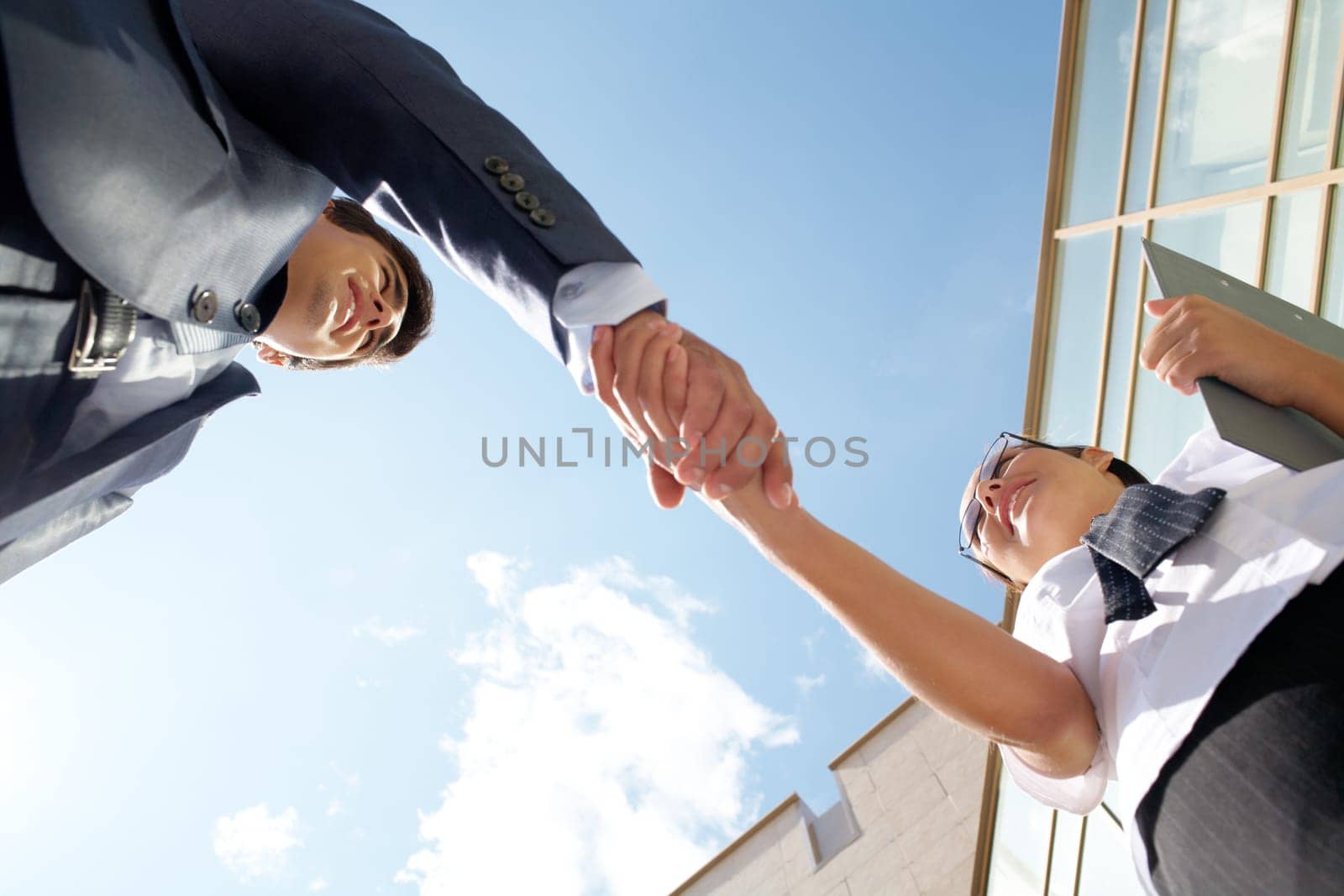 Below angle of successful partners handshaking after striking deal at meeting
