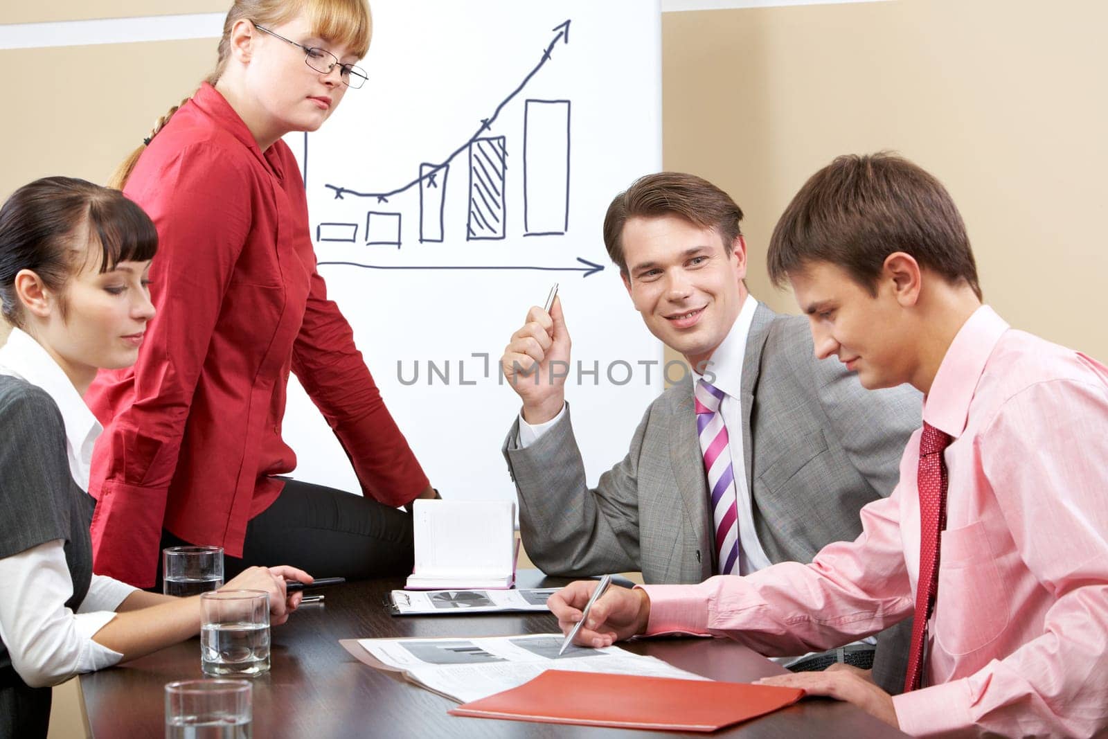 Portrait of successful team listening to young man pointing at document