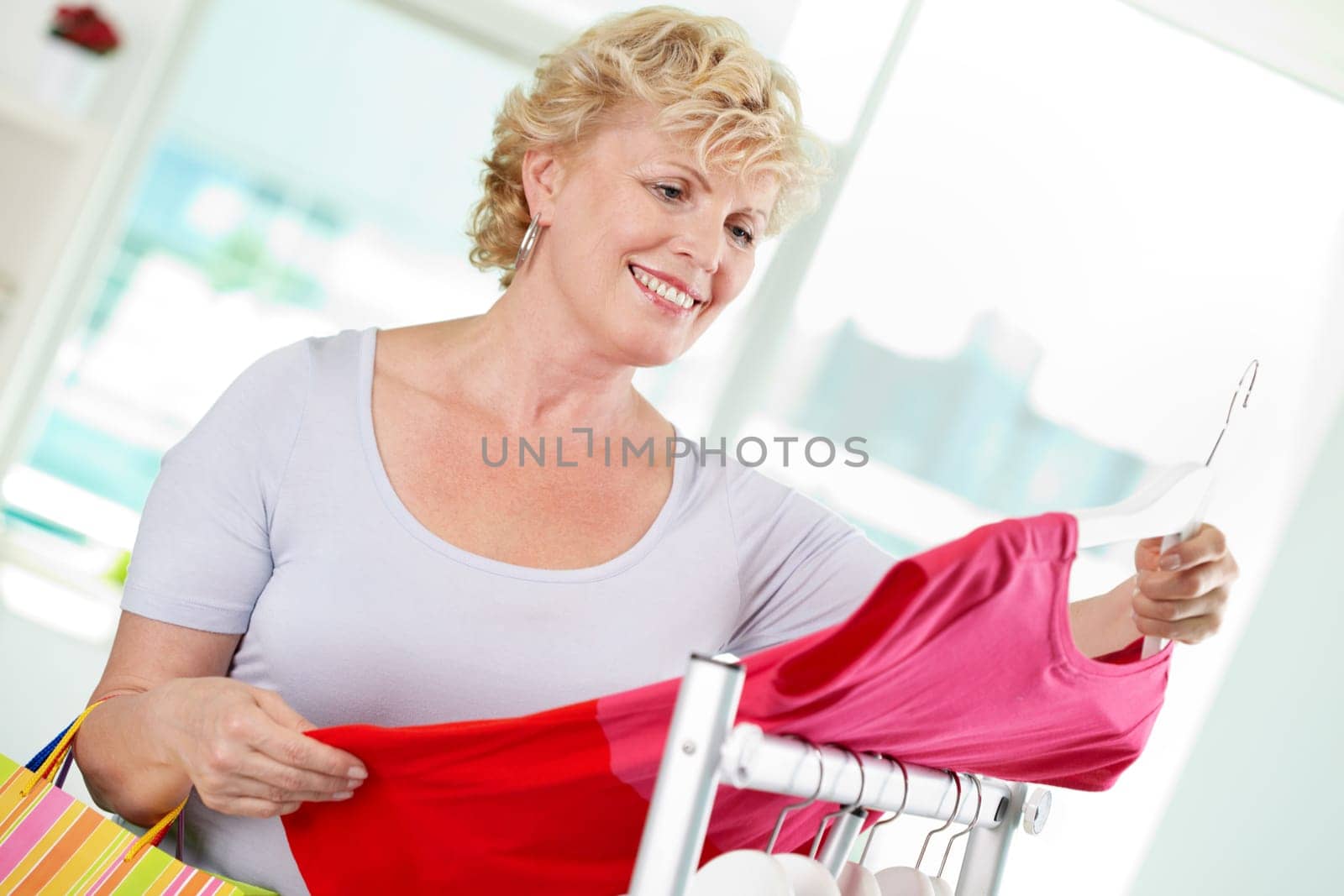 Portrait of middle aged woman choosing new tanktop in clothing department