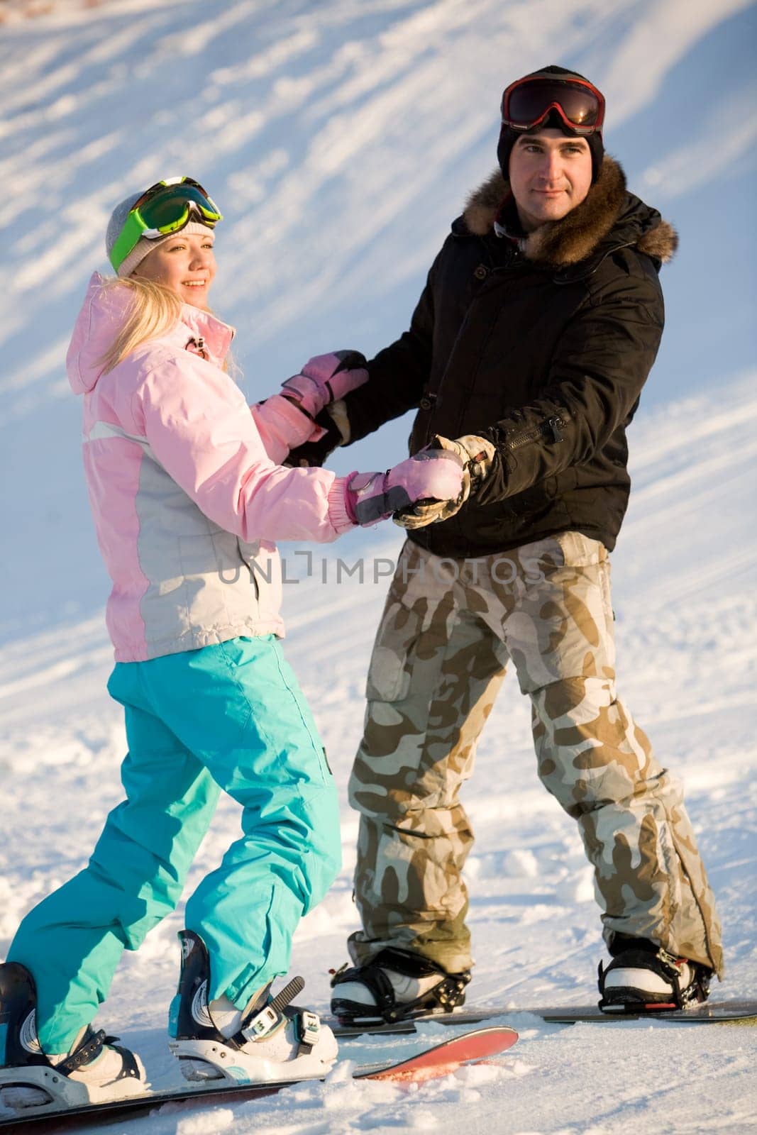 Photo of two snowboarders holding each other by hands while on the snow