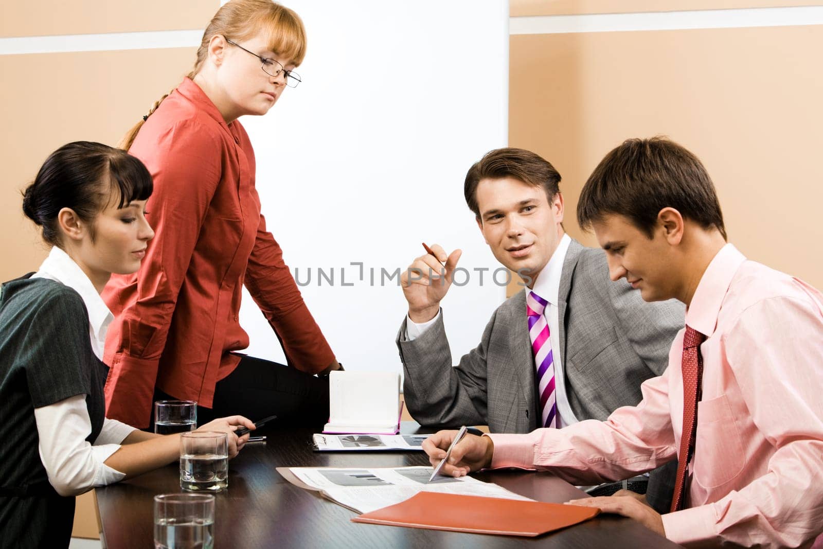 Portrait of successful team listening to young man pointing at document