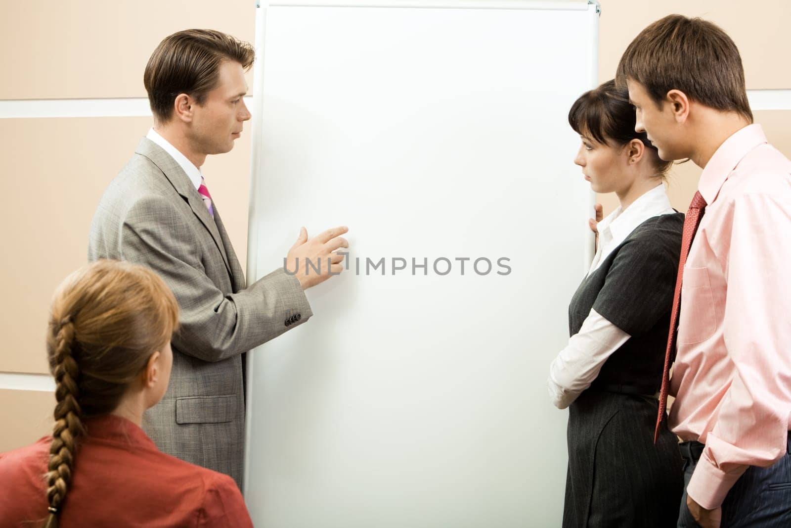 Portrait of serious business people looking at man pointing at it