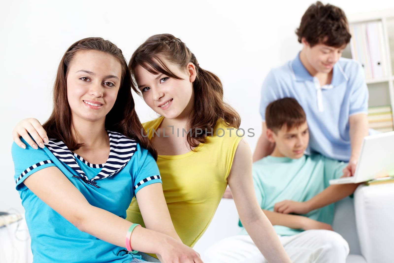 Two teenage girls looking at camera and smiling against their boyfriends