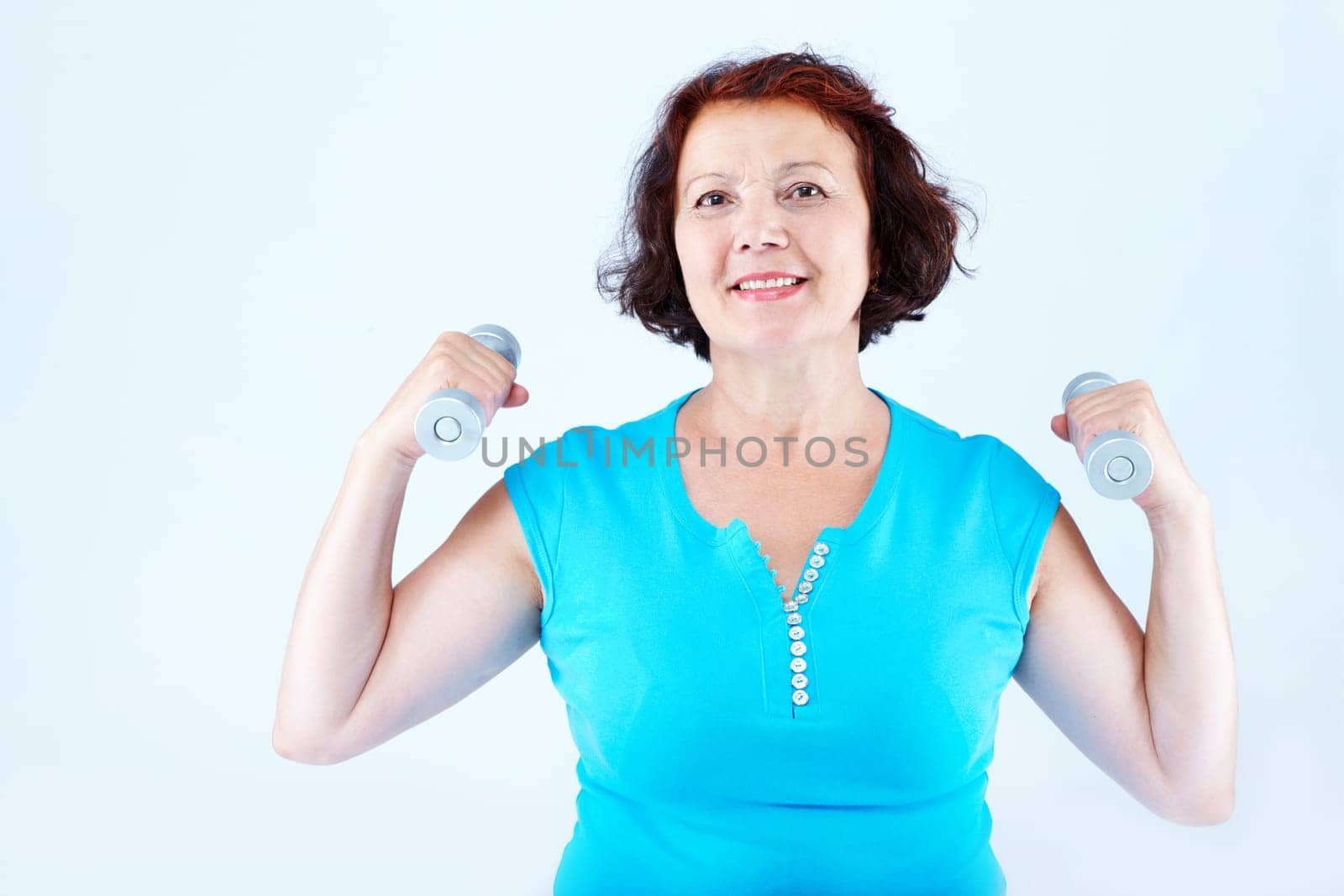 Portrait of healthy middle-aged female practicing exercise with dumbbells