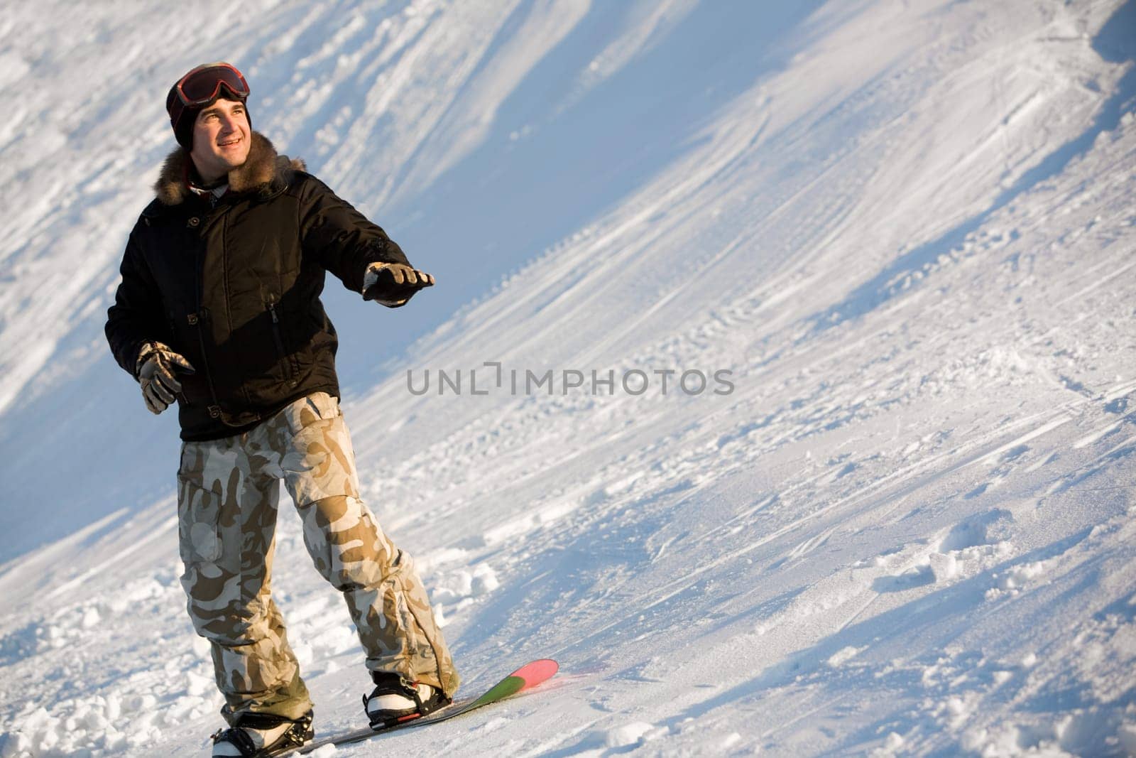 Photo of cheerful man standing on snowboard at winter resort