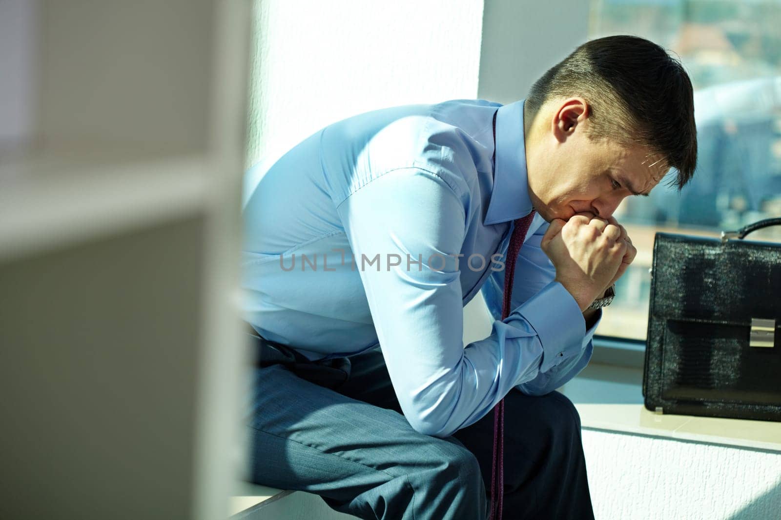 Portrait of troubled man sitting by window and trying to concentrate