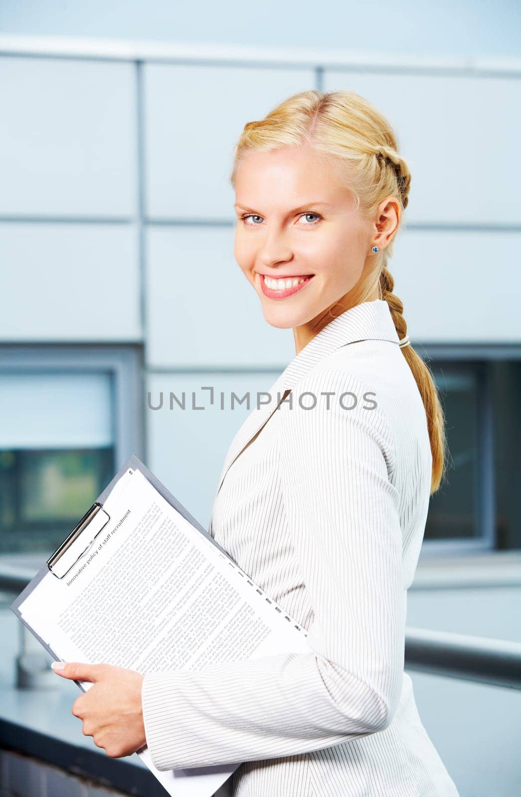 Portrait of elegant businesswoman with clipboard looking at camera