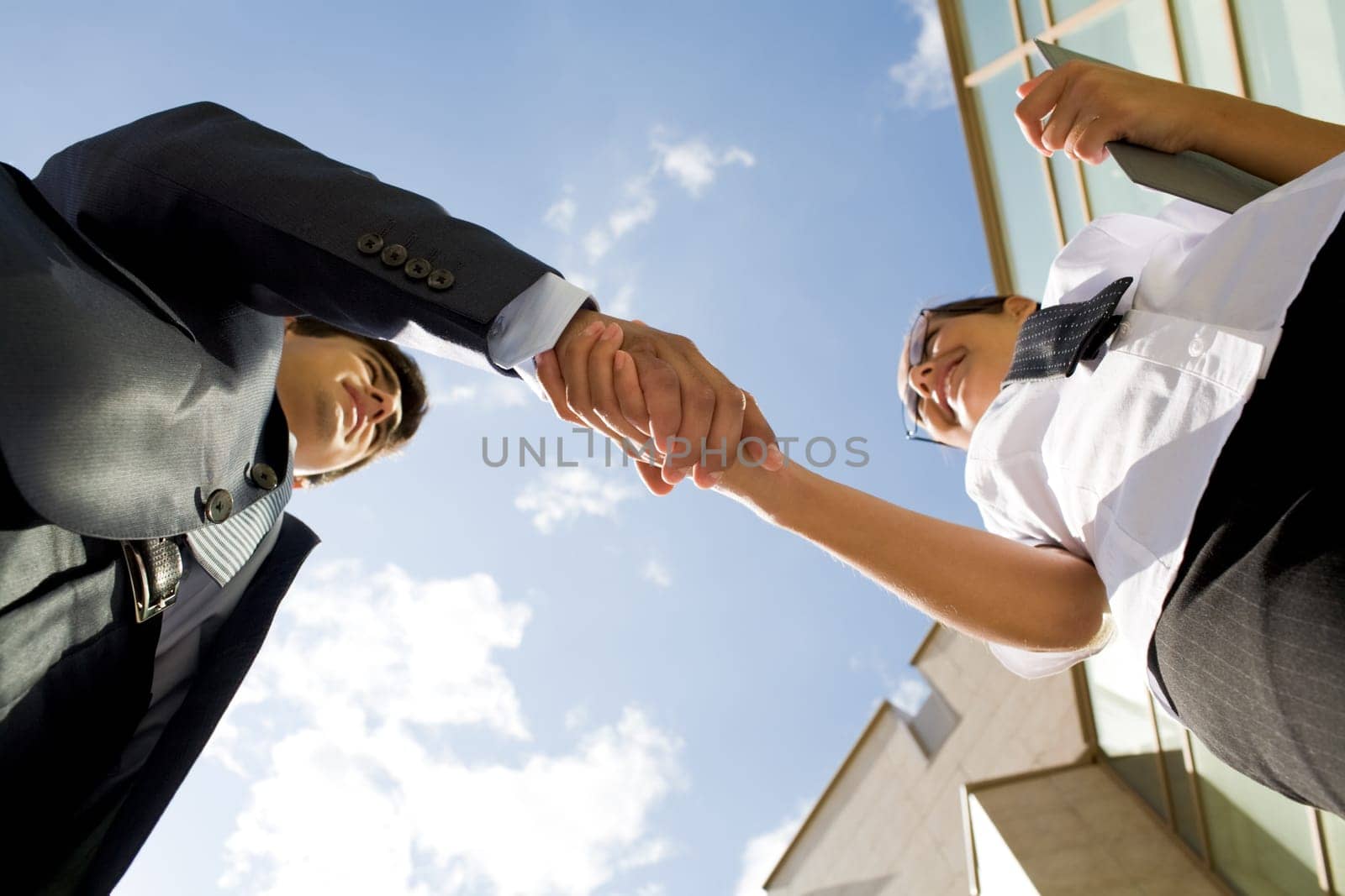 Below angle of successful partners handshaking after striking deal at meeting