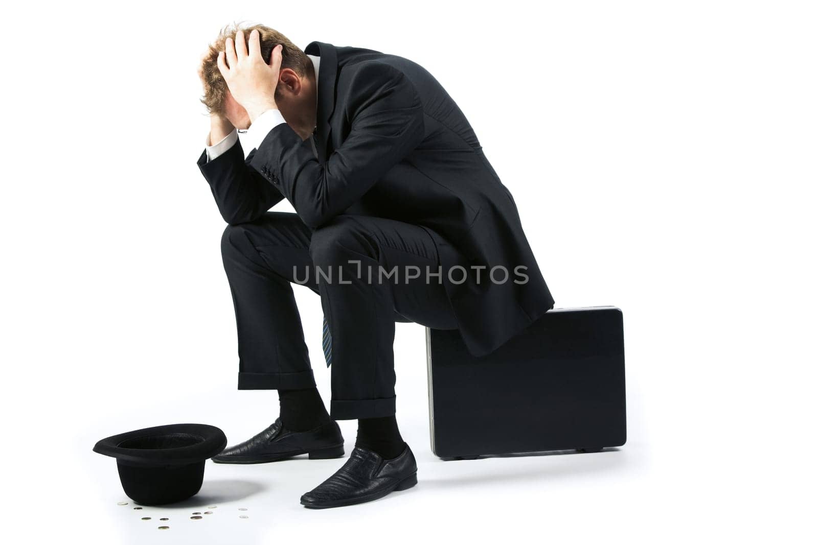 Portrait of sad businessman sitting on the floor with hat and coins near by