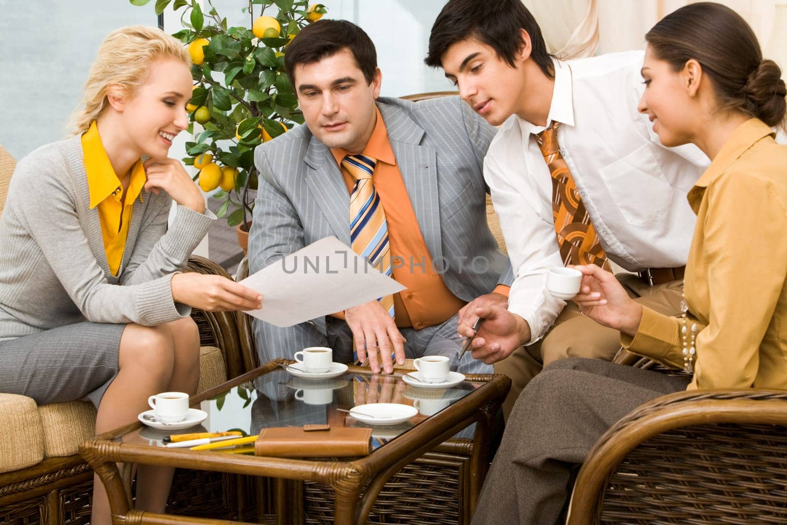Portrait of successful people communicating in office around table and having tea
