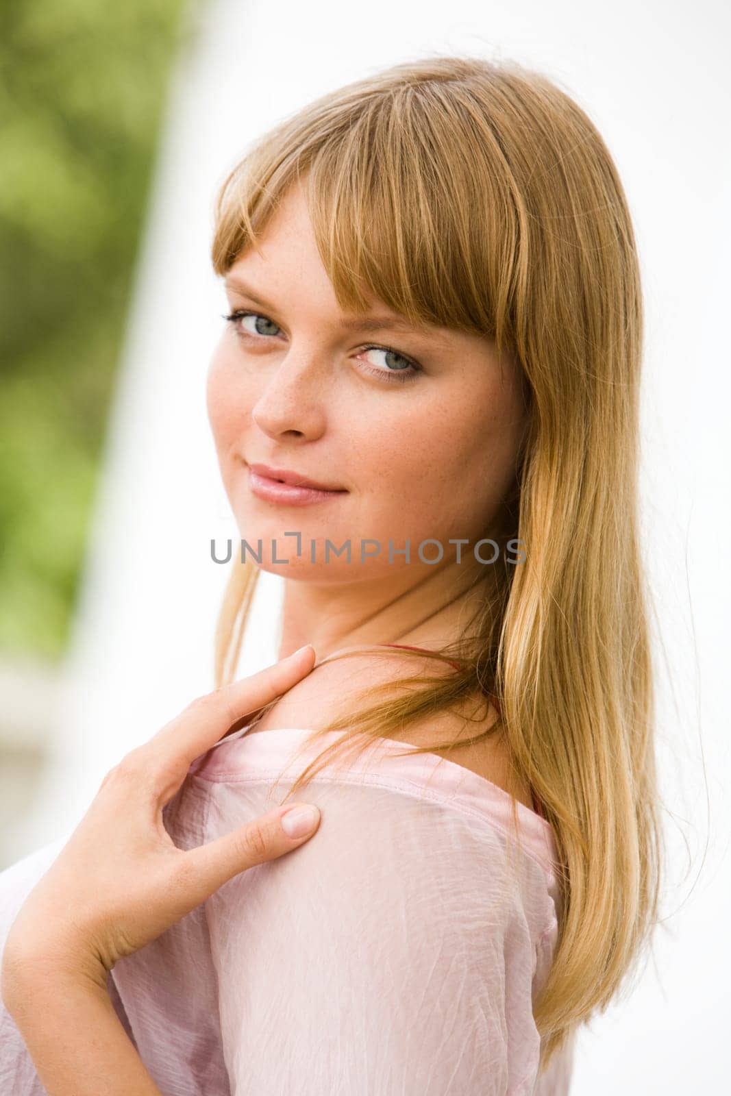 Portrait of fashionable woman touching her shoulder and looking at camera from aside