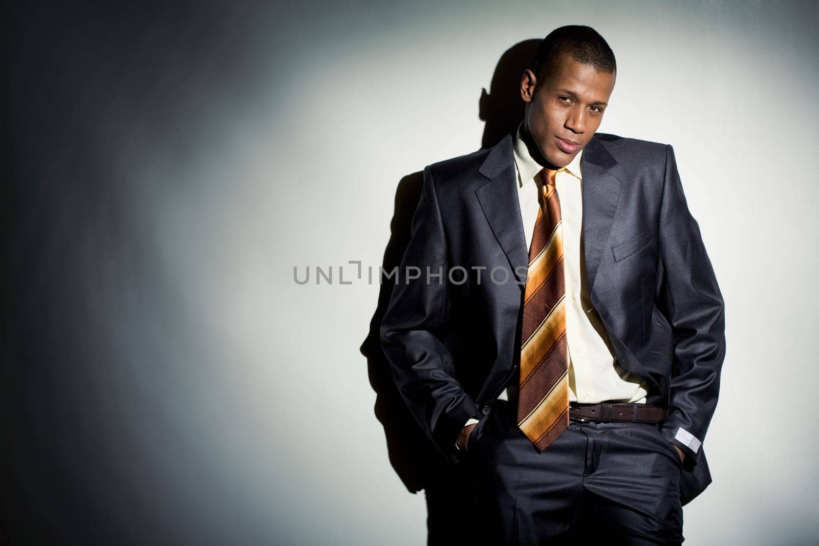 Elegant and smart male in suit standing by the wall in dark room