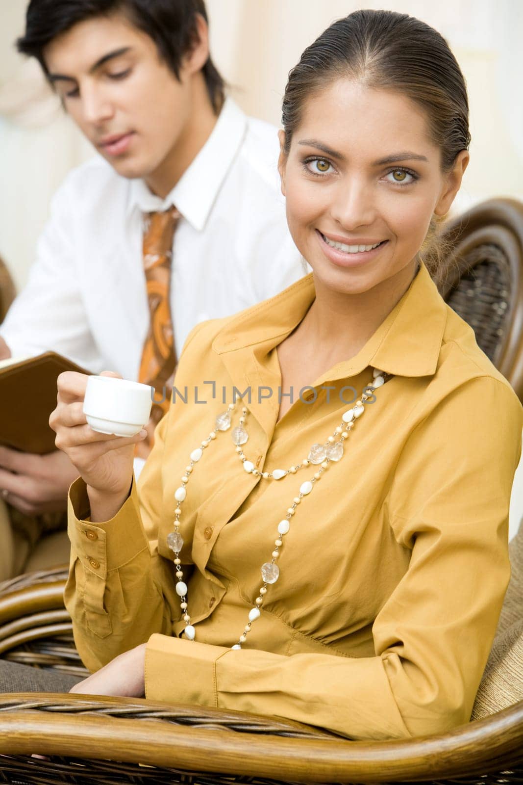 Portrait of elegant business lady with cup of coffee in hands on background of handsome man