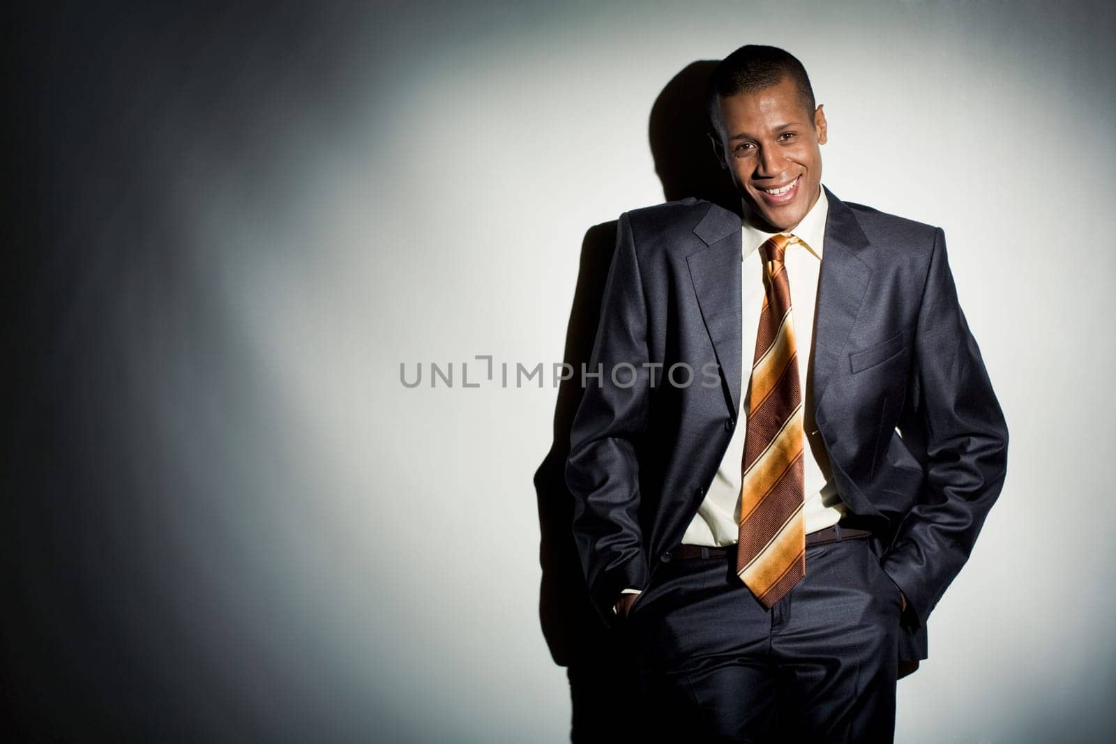 Portrait of smiling employer standing by lit wall and looking at camera