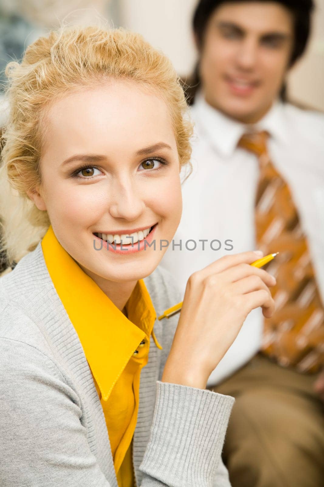 Portrait of blond woman looking at camera with smile on background of man