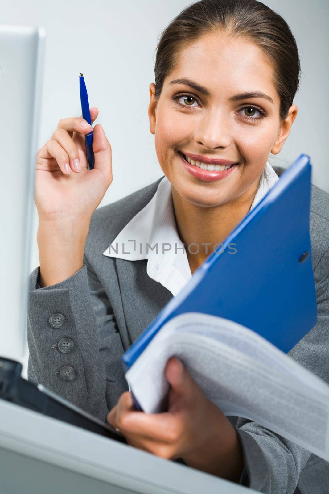 Portrait of smiling business women holding the pen, blue folder and papers in a room