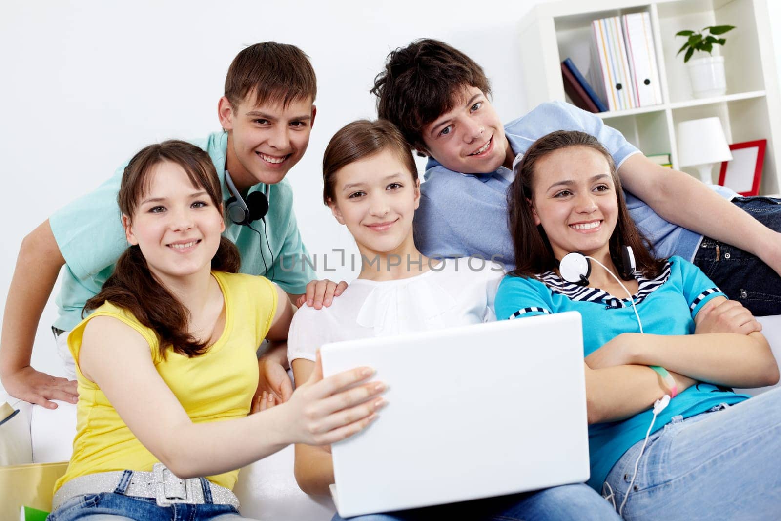 Portrait of five teens sitting on sofa with a laptop