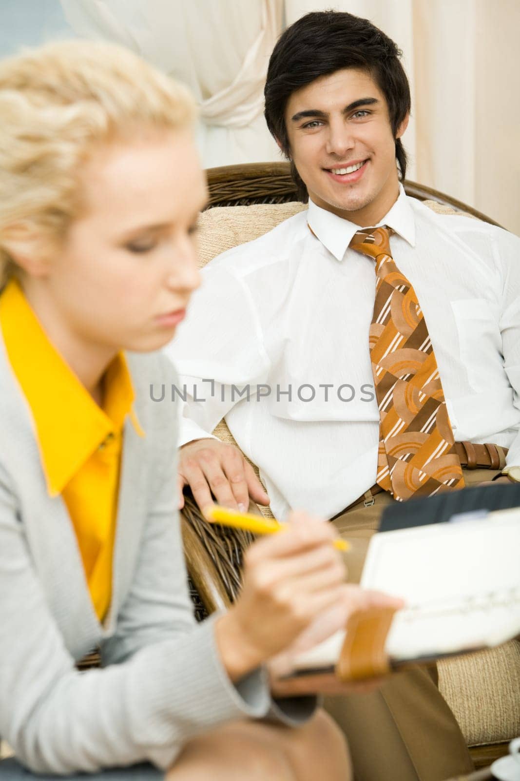 Businessman smiling at background with working female in front