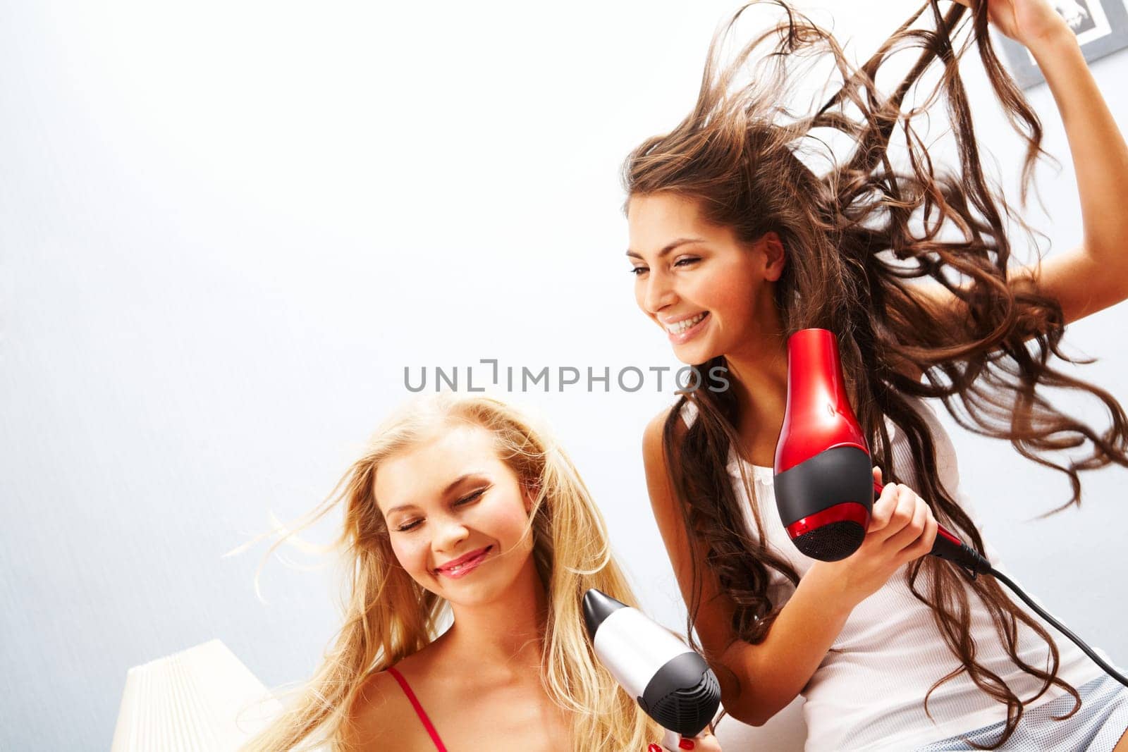 Photo of joyful females drying their hair and having fun