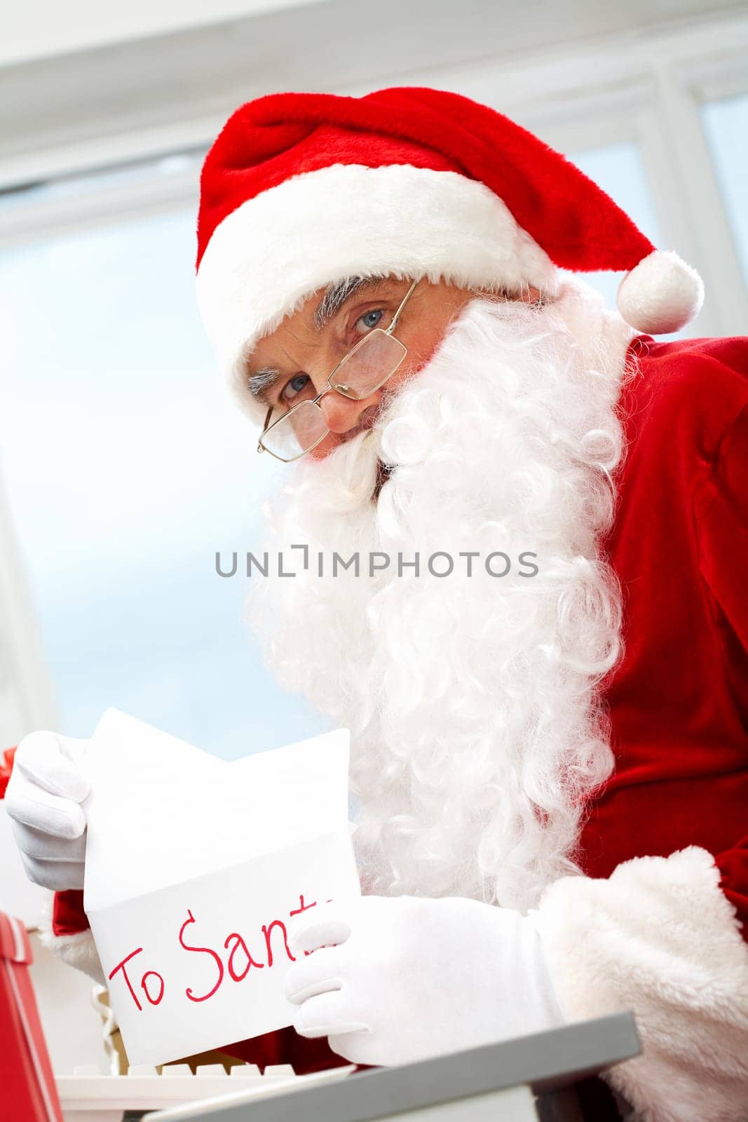 Photo of happy Santa Claus opening letter with Christmas wish