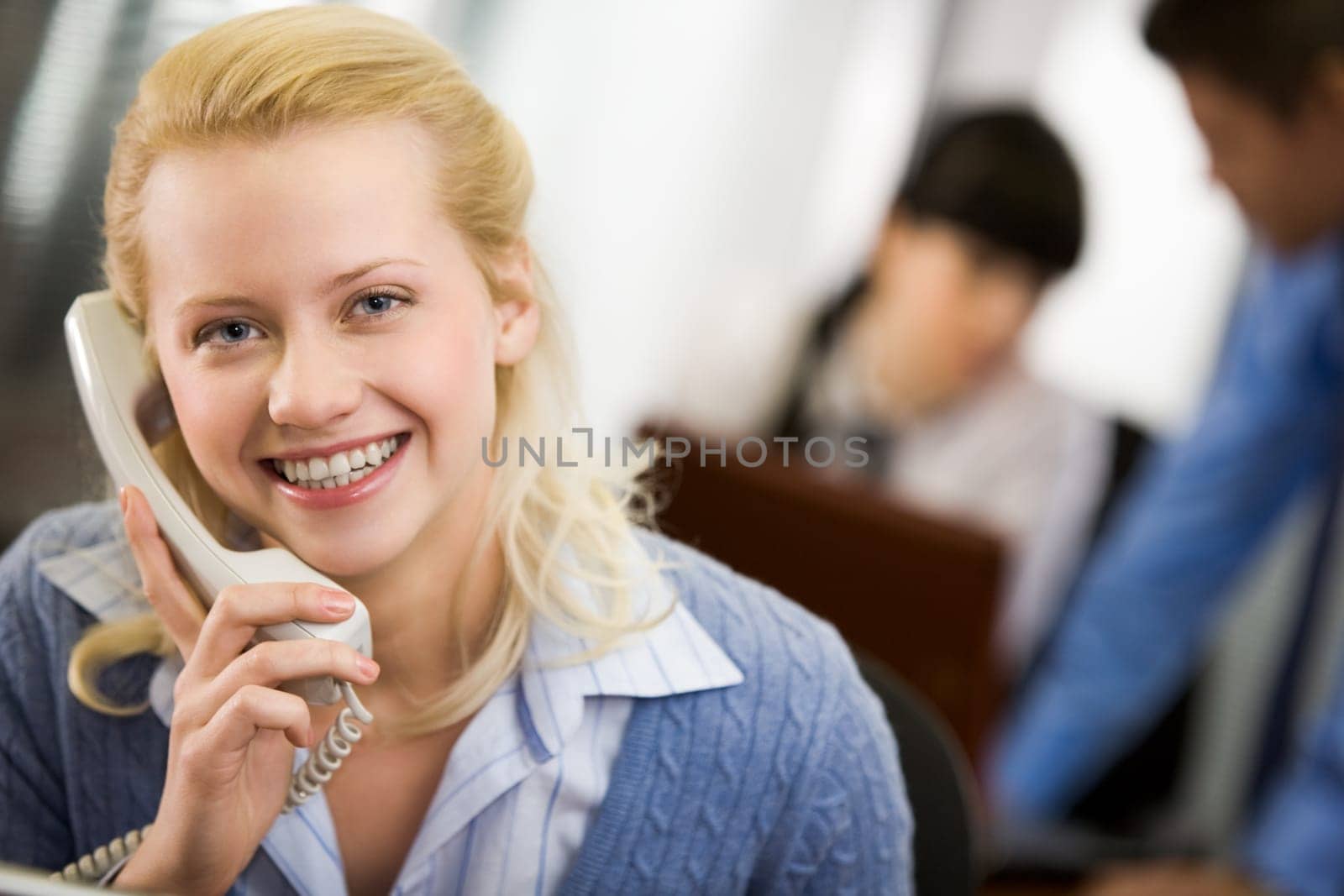 Pretty secretary speaking on the phone and looking at camera