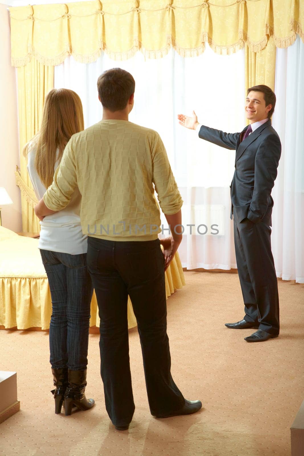 Confident businessman showing new flat to young couple