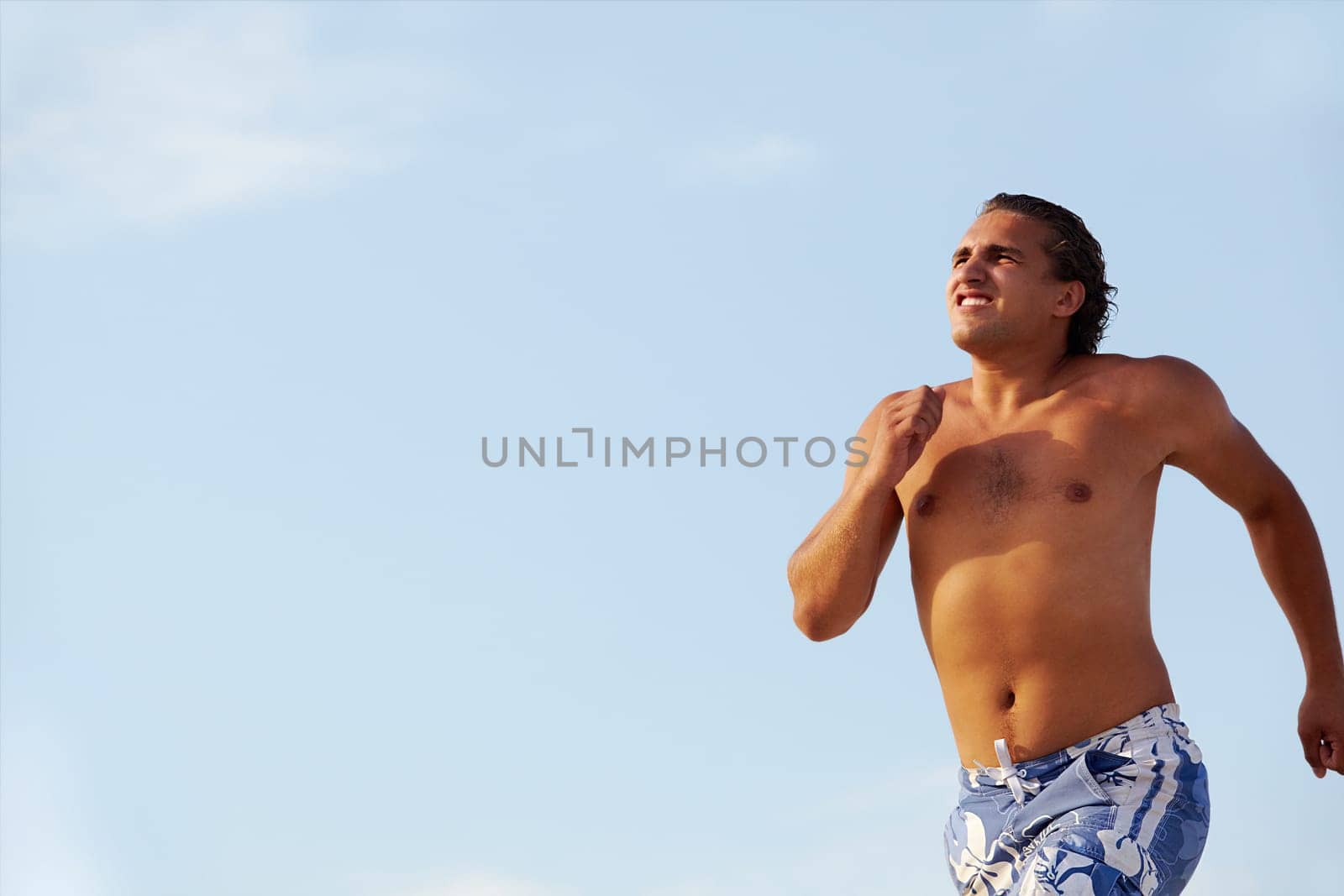 Photo of fit and healthy man running on background of blue sky