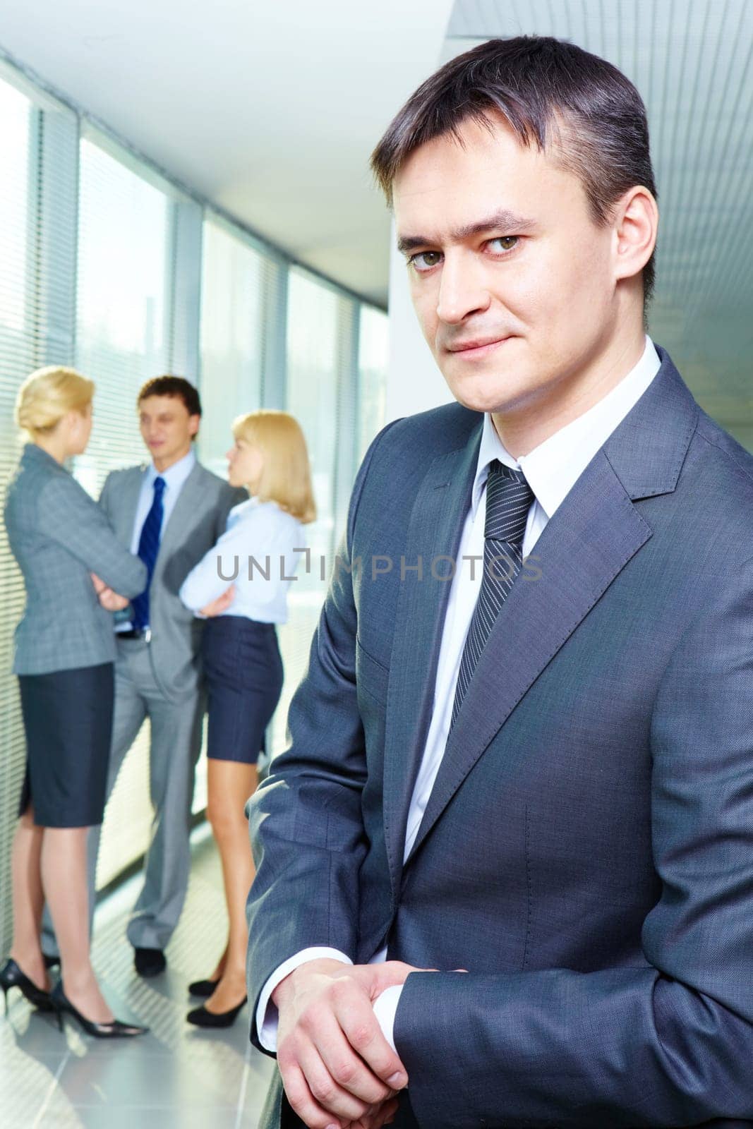 Portrait of a young confident businessman with working team on background