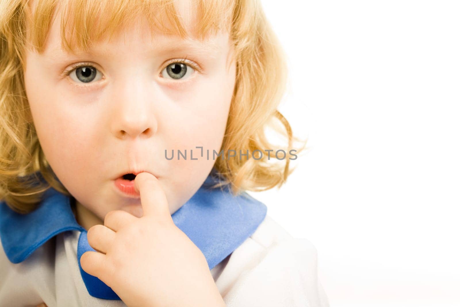 Portrait of cute little girl putting her finger to the mouth and looking at camera