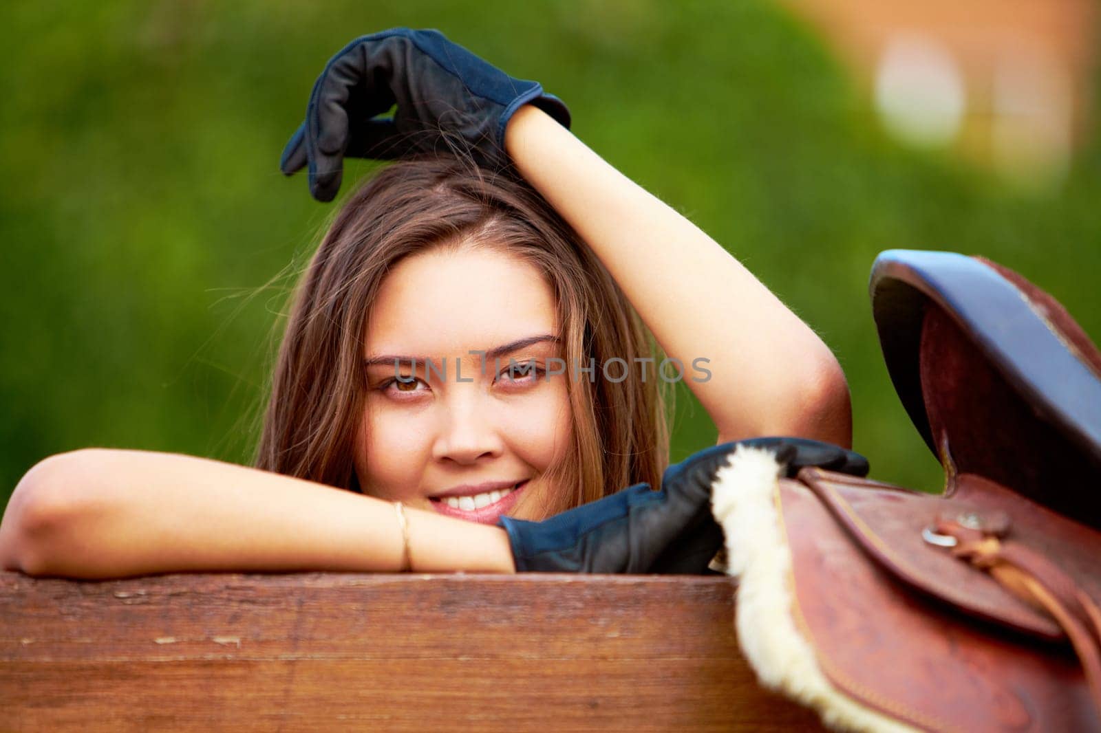 Image of happy female holding saddle and looking at camera