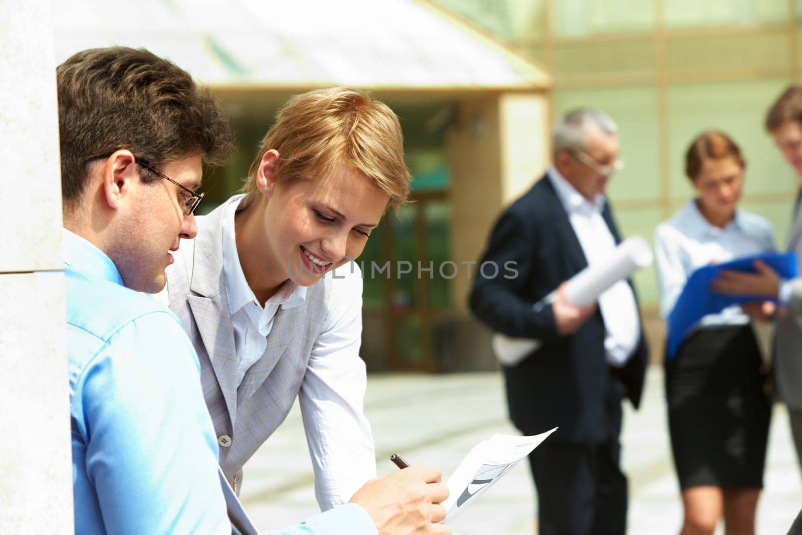 Image of business partners discussing document outdoors