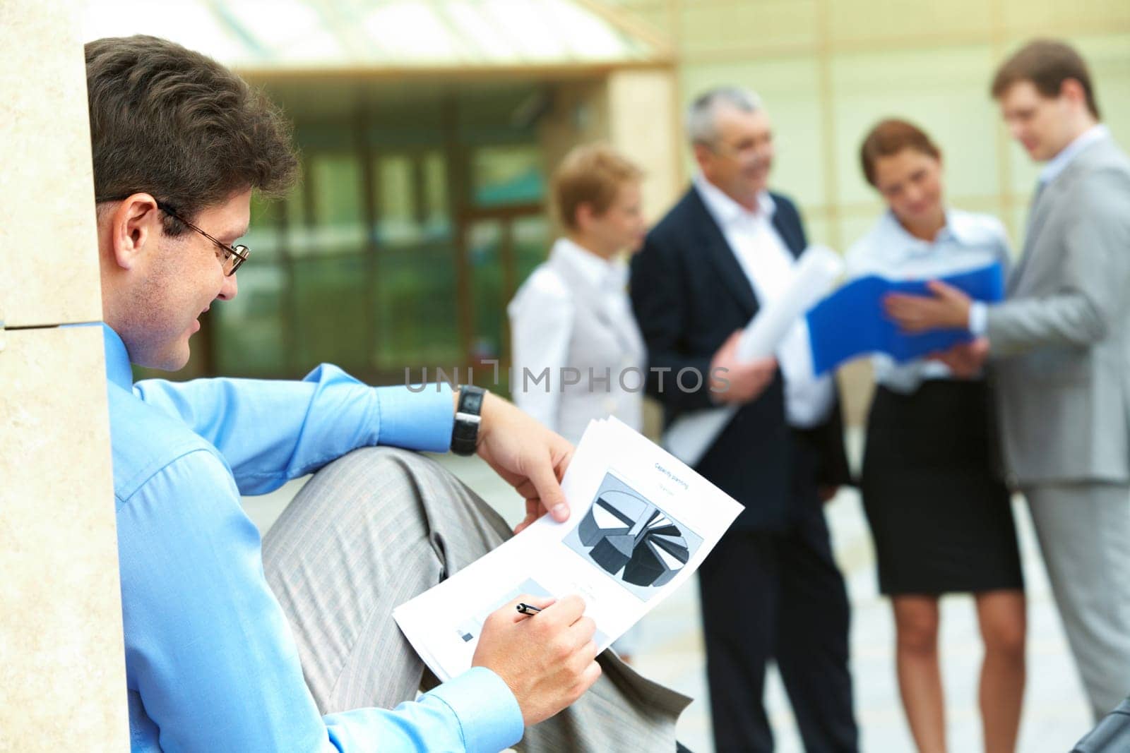 Image of businessman sitting outside and working with document