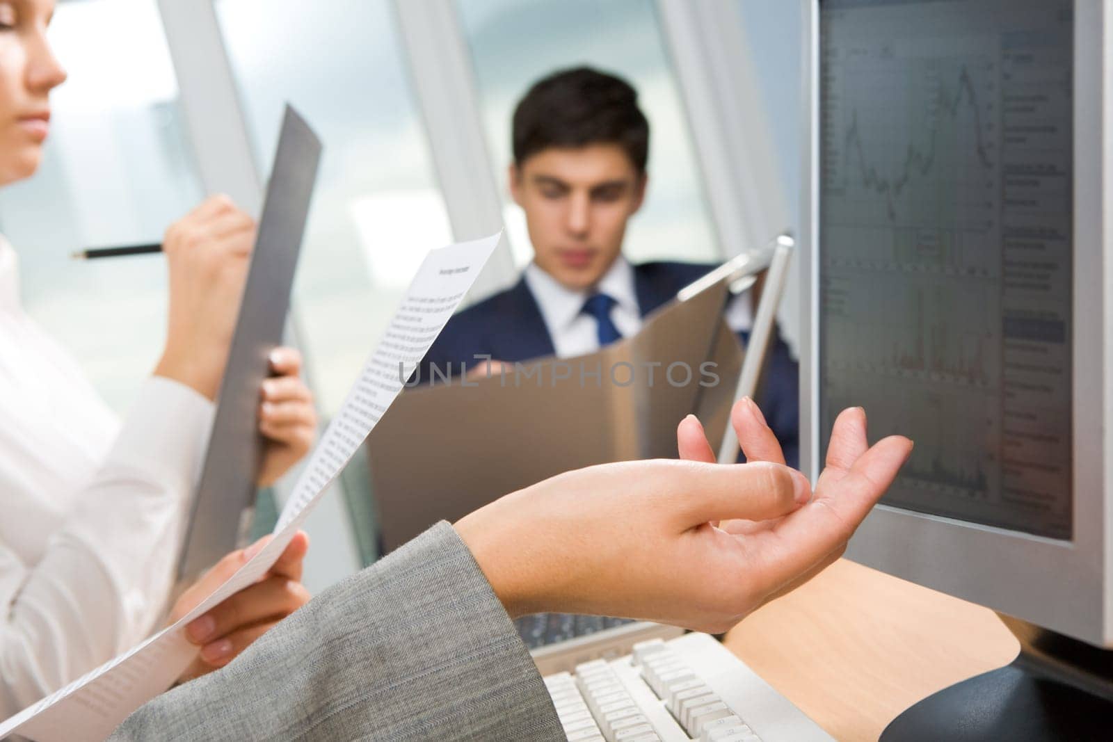 Close-up of female hand with paper on background of secretary and working man