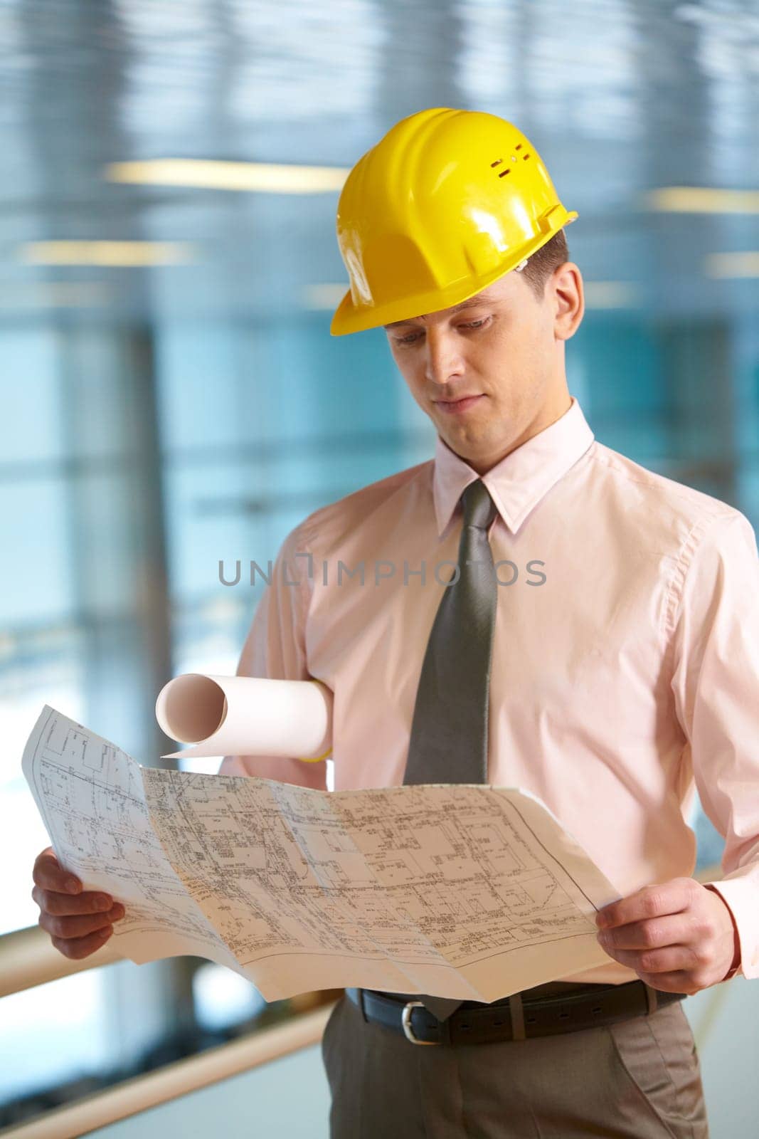 Young architect in helmet examining a housing plan