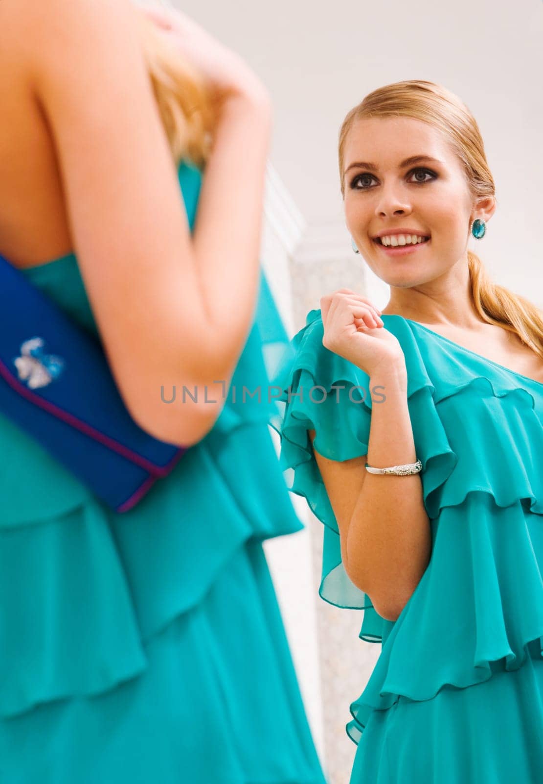 Image of pretty female in green dress looking in mirror with smile
