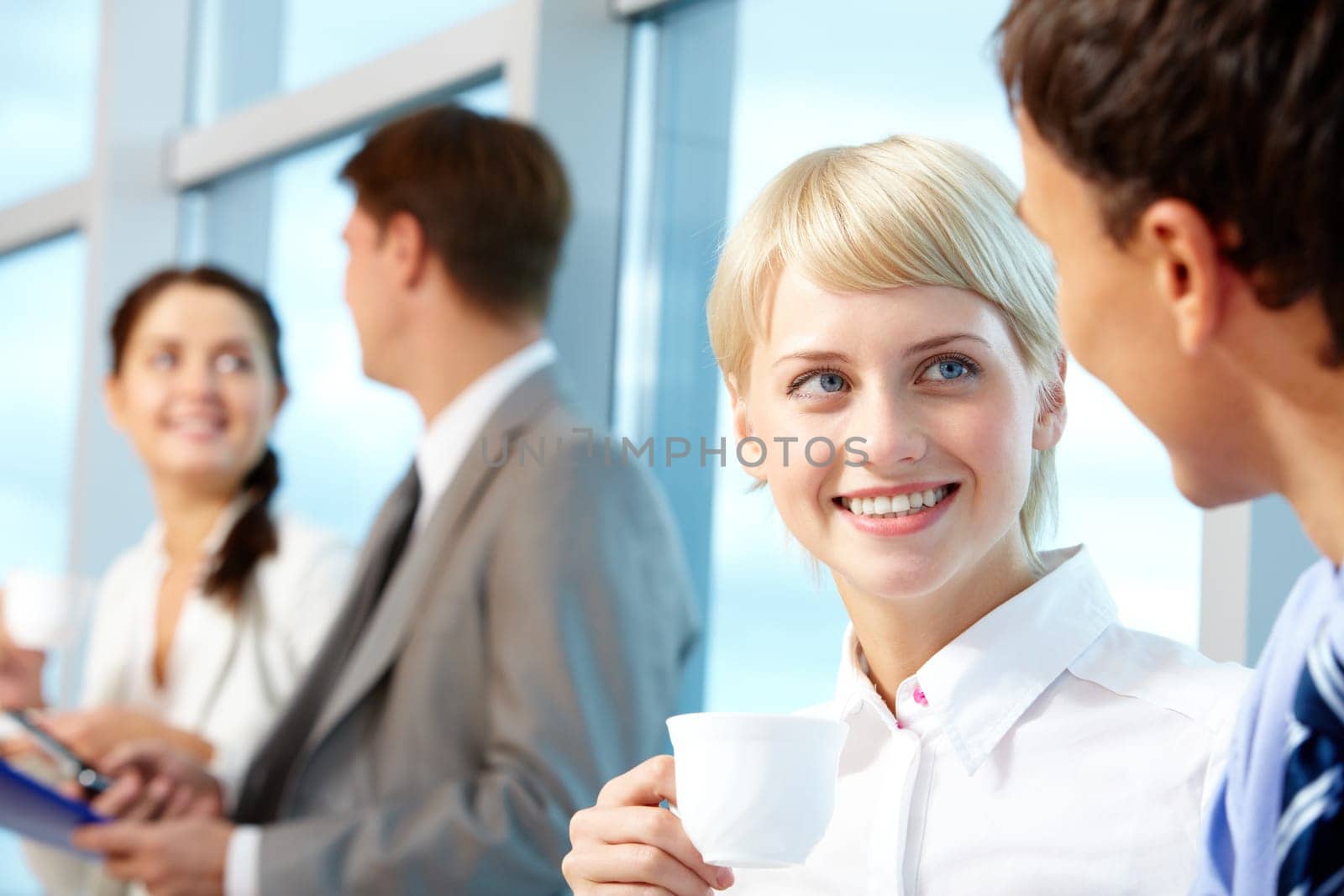 Portrait of young female with cup of coffee looking at her partner while listening to him
