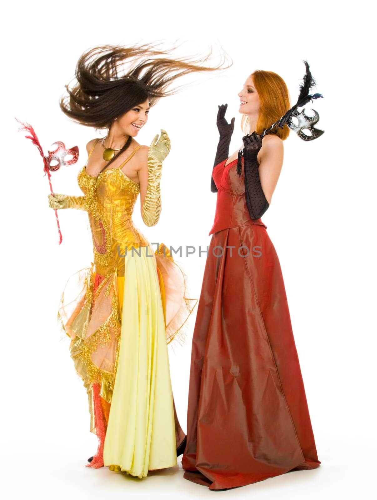 Photo of joyful actresses in fashionable dresses having fun over white background