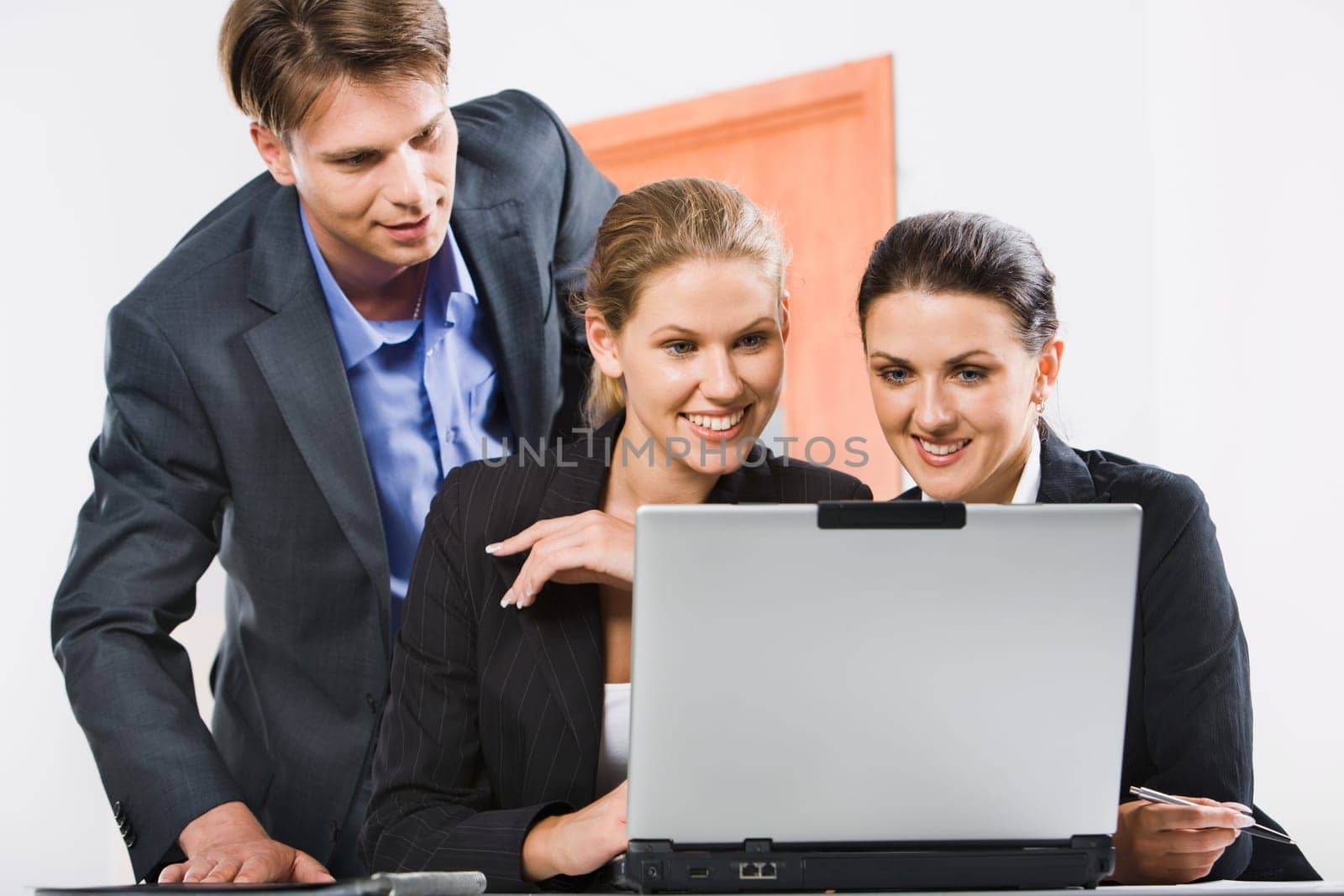 Businessman is looking at computer worked by two colleagues