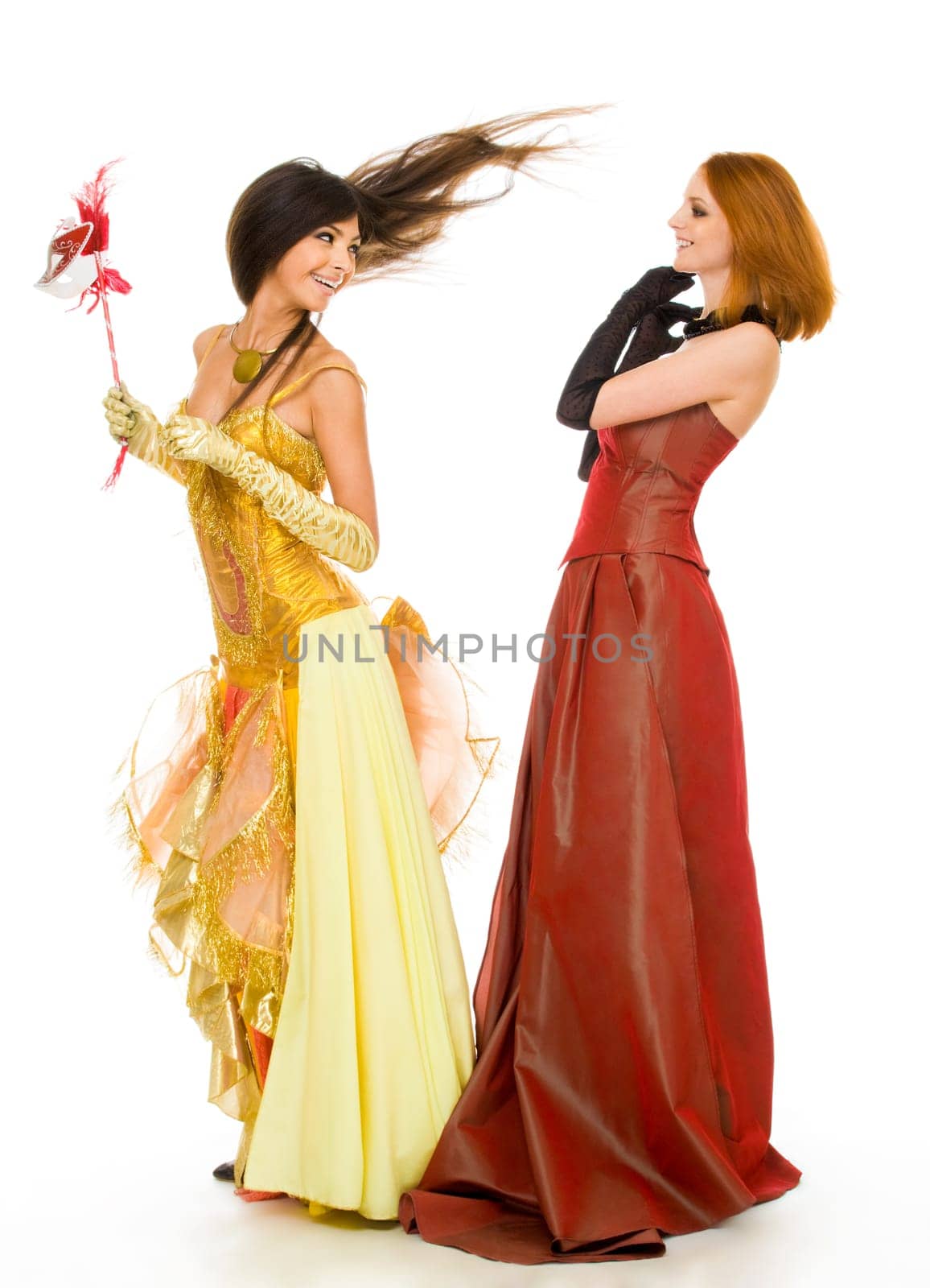 Photo of joyful actresses in fashionable dresses having fun over white background