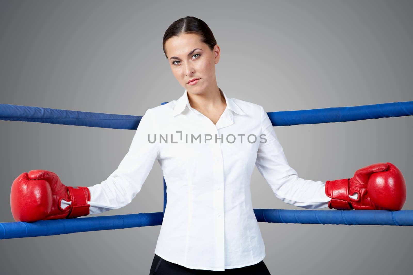 Portrait of strict businesswoman in boxing gloves looking at camera