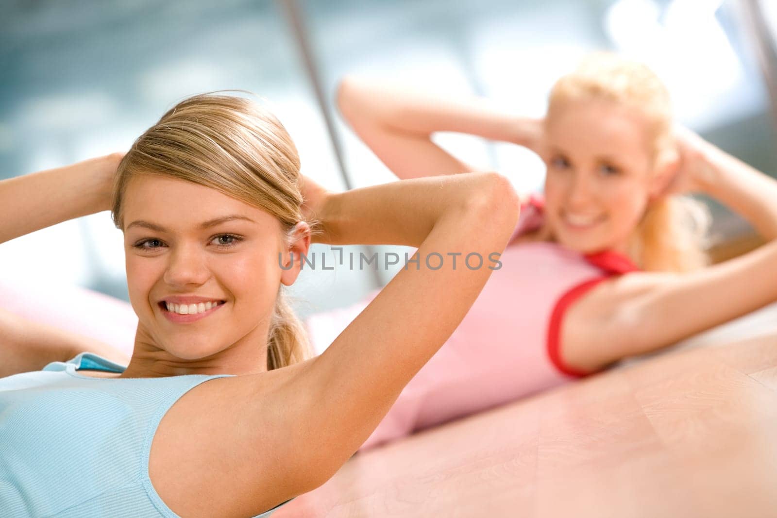 Photo of cheerful girls doing exercise on the floor of sport gym