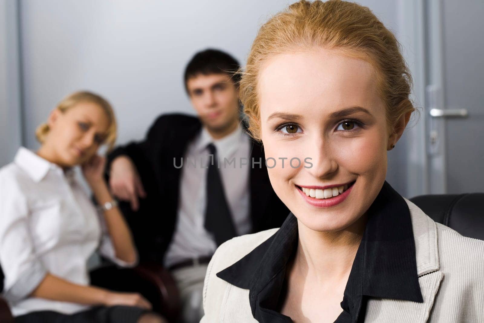 Portrait of smiling businesswoman and two her partners on the background