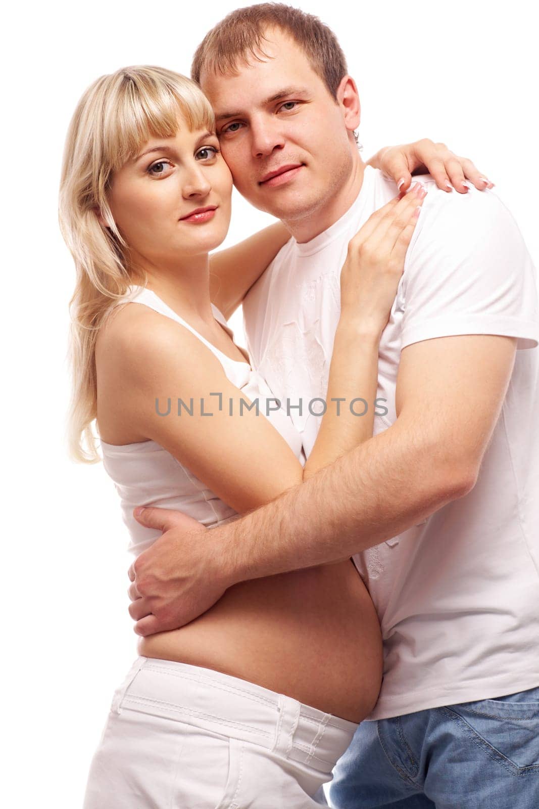 Image of pregnant woman and her husband embracing and looking at camera